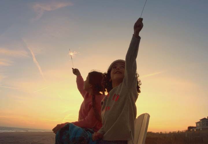 two young girls holding sparklers at a Hamptons beach